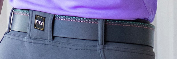 Gray pants with a purple shirt and FITS belt on a light gray background