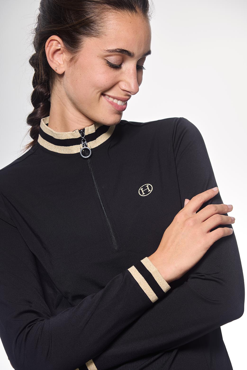 Woman wearing a black equestrian shirt with beige accents on a white background
