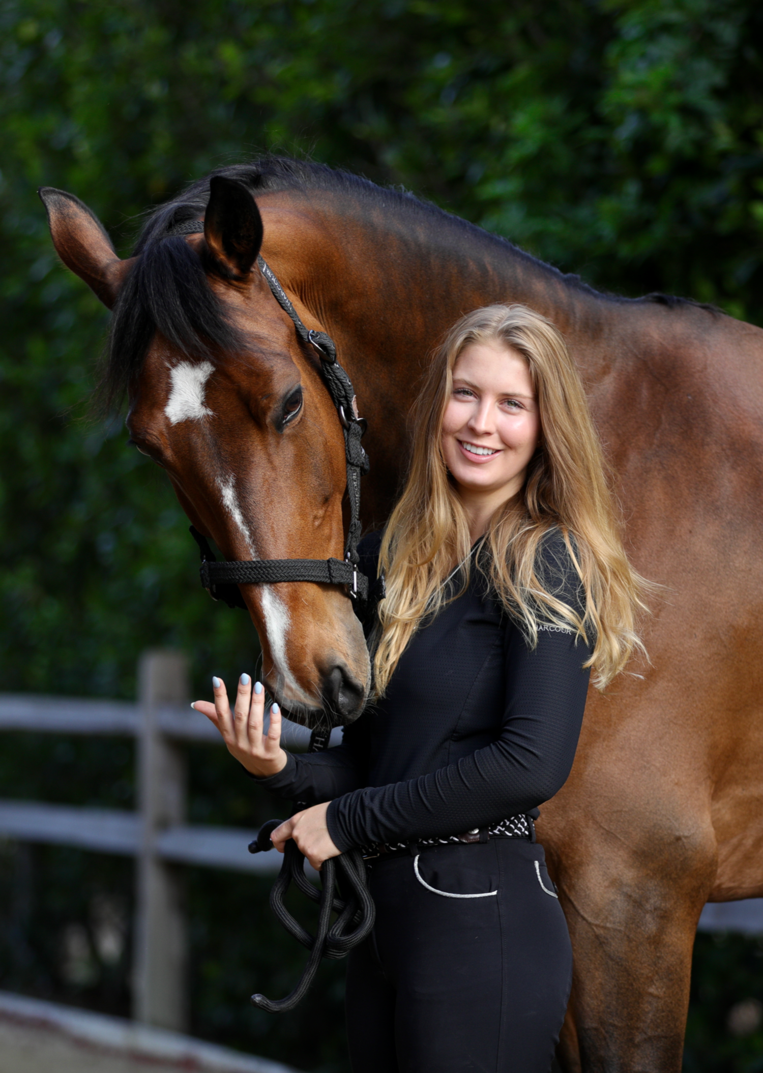 Woman standing next to a horse with a blurred green background