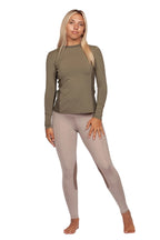 Woman wearing a green long-sleeve top and beige leggings on a white background