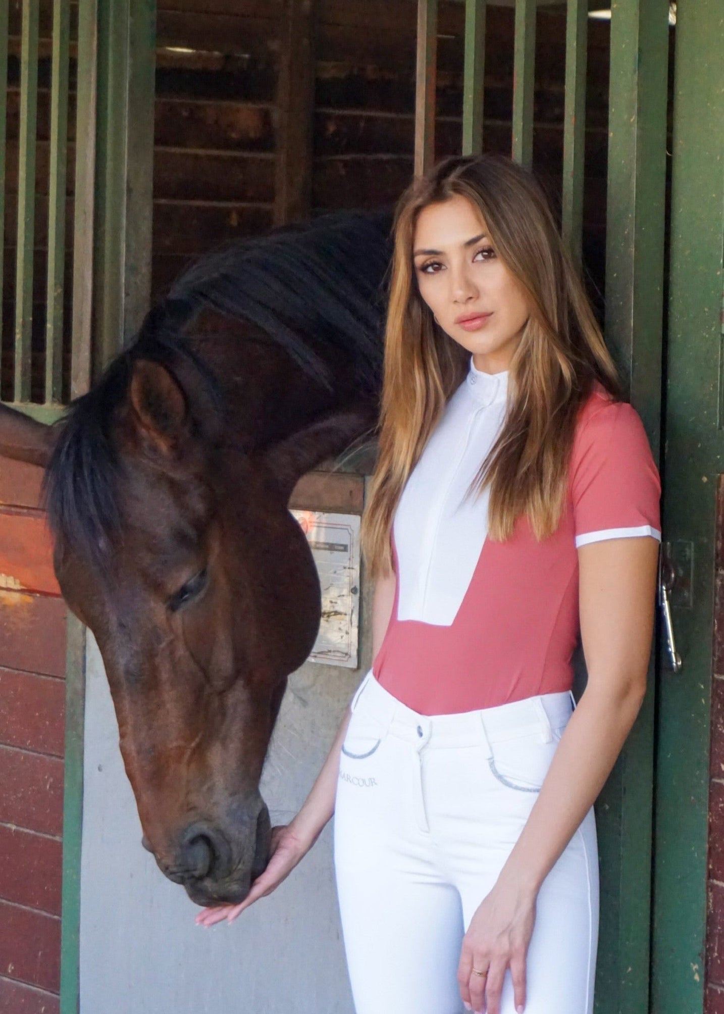 Woman standing next to a horse in a stable