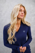 Woman wearing a navy blue sweater with a logo on a gray background
