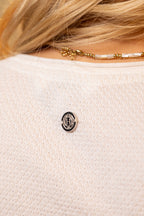 Close-up of a white textured garment with a brand logo on a blurred background