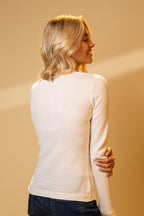 Woman wearing a white sweater against a beige background