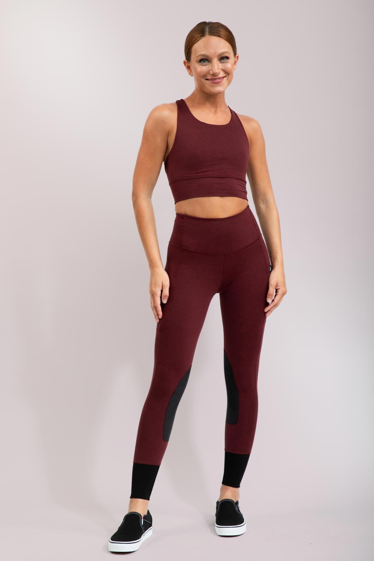 Woman wearing a maroon athletic outfit on a light gray background