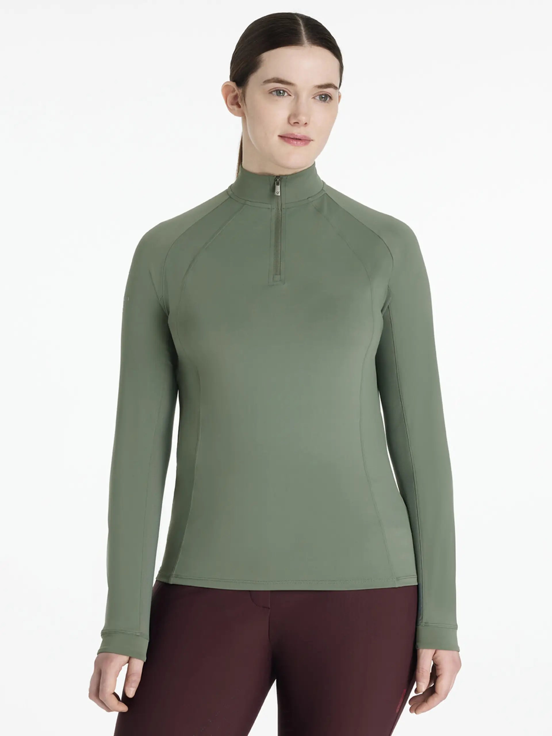 Woman wearing a green long-sleeve top with a quarter zip on a white background