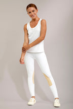 Woman wearing a white tank top and leggings with beige accents on a gray background