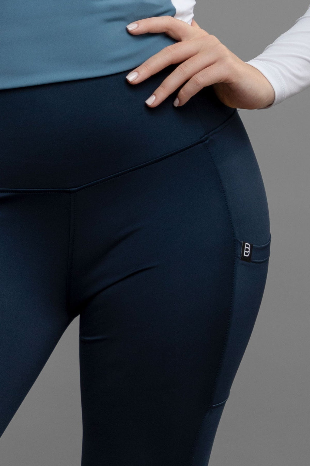 Navy riding leggings with a small logo on a gray background