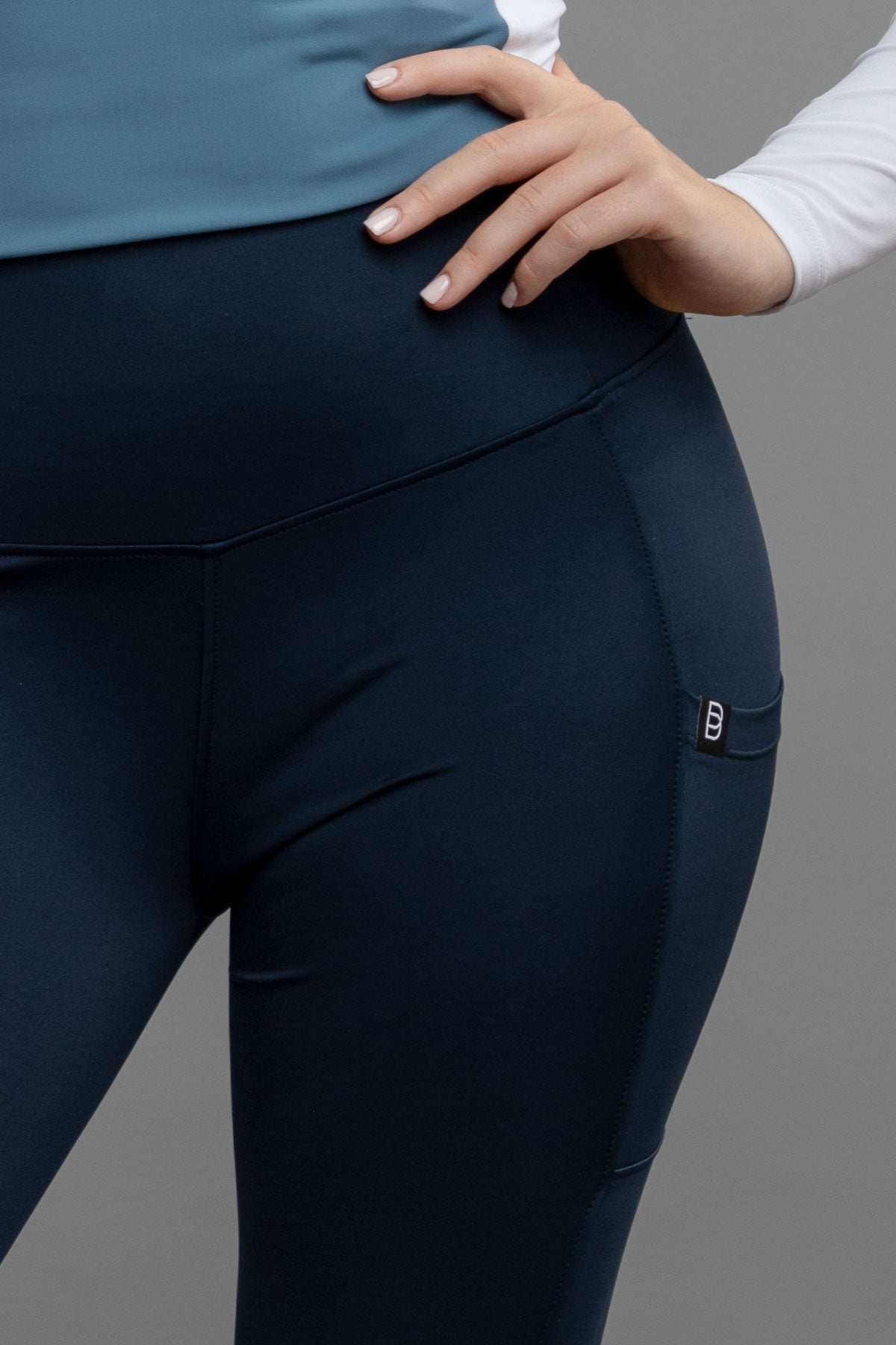 Navy riding leggings with a small logo on a gray background