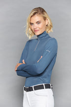 Woman wearing a blue long-sleeve top with a zipper against a gray background