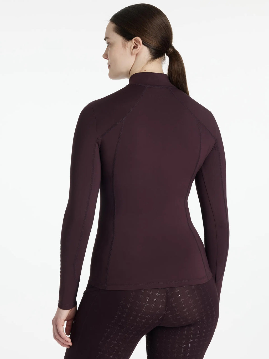 Woman wearing a maroon long-sleeve top on a white background