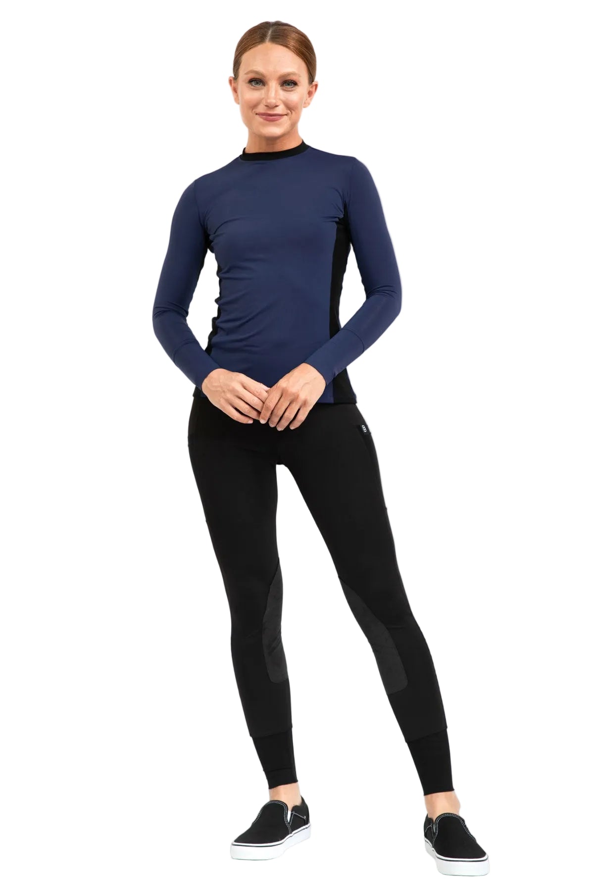 Woman wearing a navy long-sleeve top and black equestrian riding leggings on a white background