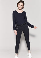 Woman wearing a black long-sleeve top and black pants on a light gray background