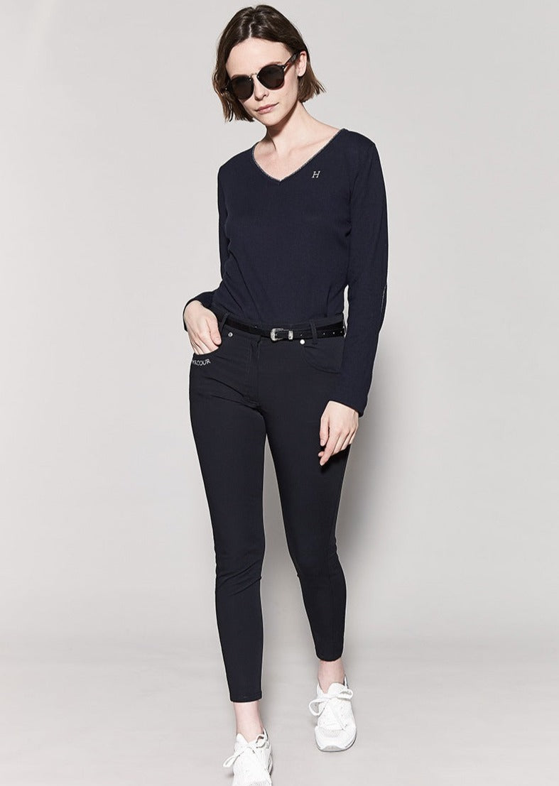 Woman wearing a navy blue outfit with white sneakers on a light gray background